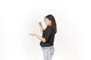 beautiful Asian woman poses with open hands, gesturing toward empty space to showcase a product against a white background photo