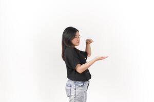 beautiful Asian woman poses with open hands, gesturing toward empty space to showcase a product against a white background photo