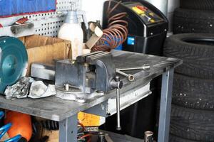 Mess on a working table with metallic tools and metal vice, tires pressure, garage workshop photo