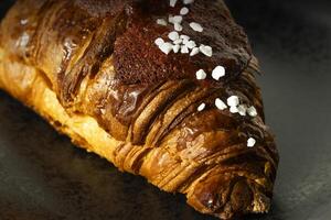 Freshly baked French pastry on black background with jam. Closeup photo. Buttered bread croissant on black photo
