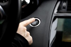 Women activates button to start and stop for car engine, pressing start engine button on a modern sports car photo