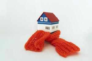 House wrapped in scarf on white background, space for text. Winter heating efficiency photo