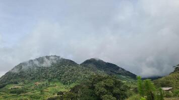 A lush green valley with rolling hills and scattered clouds in the sky. photo