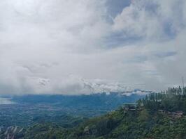 A scenic view of a lush green landscape with a lake surrounded by mountains under a cloudy sky. photo