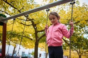 Young girl playing on a swing in autumn park setting photo