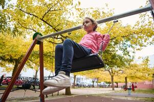 Young girl enjoys a sunny day on a swing in the park photo