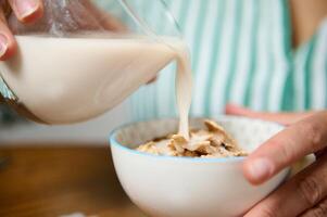 Pouring milk into a bowl of healthy whole grain cereal photo