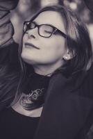A serene moment captured of a woman enjoying nature with closed eyes, adorned in a stylish outfit and glasses during a sunny day outdoors photo