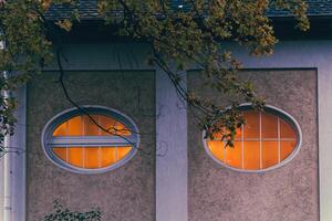 Illuminated oval windows are set into the textured facade of a building photo