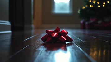 A red bow on the floor in front of a christmas tree photo