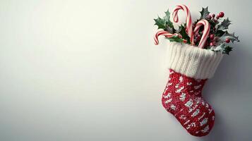 Christmas stocking with candy canes and holly on white background photo