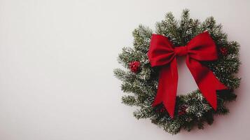 A wreath with red ribbon and pine needles on a white wall photo