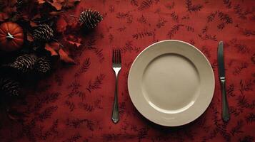 A white plate with a fork and knife on a red tablecloth photo