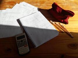 A calculator, a notebook, and a red bag on a table photo