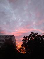 A sunset with clouds and trees in the background photo