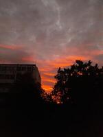 A sunset with clouds and trees in the background photo