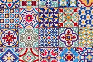 A spanish of decorative ceramic tiles displays an array of intricate patterns and vibrant colors, including blues, reds, and greens photo