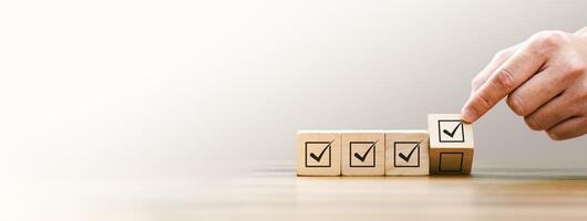 Close-Up of a Hand Arranging Wooden Blocks with Checkmarks Symbolizing Task Completion and Goal Achievement, Representing Productivity, Workflow, and Success in Business and Personal Organization photo