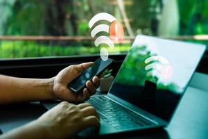 Person Holding Smartphone and Laptop with Wi-Fi Connection Error Warning in Modern Workplace. Internet Connectivity Issues Symbolized by Red Alert Icons on Devices, Unable to connect photo