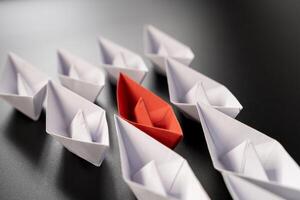 Row of paper ships on black background. Business concept of creative innovation and leadership. photo