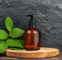 Elegant amber bottle with pump placed on wooden surface with green leaves around. photo