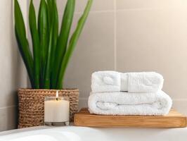 A serene bathroom scene featuring stacked towels, a candle, and a potted plant. photo