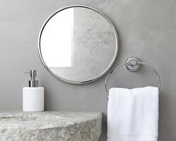 Modern bathroom with round mirror, stone sink, and white towel emphasizing minimalist design. photo