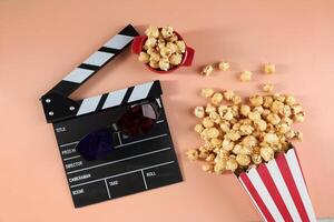Tasty Popcorn in Paper Buckets, Movie Clapper and 3D Eyeglasses on a Bright Colored Background. photo