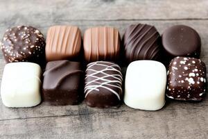 Assorted chocolate pralines arranged on rustic wooden table photo
