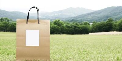 Eco friendly paper bag on a grassy field with mountains in the background photo