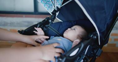 Selective focus, Hand of Young mother happily playing with little boy lying in baby stroller in a cafe. Family enjoying happy time together. Happy lifestyle. photo