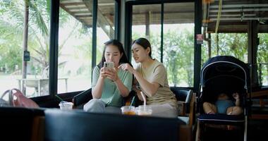 Portrait of Two siblings sit at a cafe table playing with social media on smartphone while waiting for baby boy to wake up. Family enjoying happy time together. photo