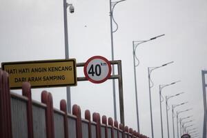 Speed Limit Warning Sign and Strong Side Wind Alert on Bridge photo