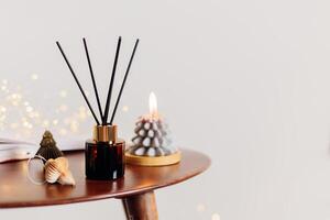 Home aroma fragrance diffuser and burning candles shape of tree on wooden table in the bedroom. Interior elements. Christmas and Winter decoration photo
