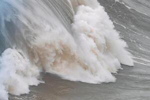 Huge wave crashing with dramatic foam and spray at Nazare in Portugal photo