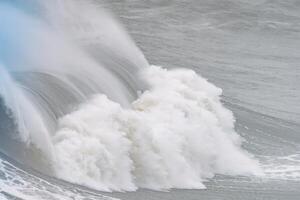 Massive ocean wave cresting with foam and spray at Nazare in Portugal photo