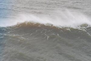 A dramatic wave breaking with white spray and turbulent motion in Nazare, Portugal photo