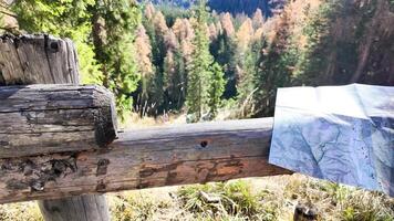 A detailed hiking map rests on a rustic wooden fence in a sunlit forest, capturing the essence of autumn exploration photo