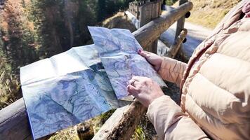 A person explores a folded map in the mountains during a fall hiking trip, emphasizing navigation and adventure photo
