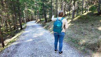 A woman with a backpack, possibly Caucasian, points direction on a forest trail, highlighting exploration and navigation challenges photo