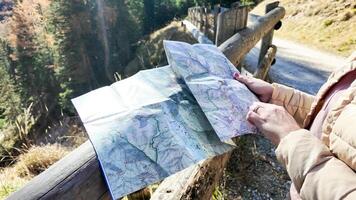 A person holding a map while navigating a scenic mountain trail, symbolizing exploration and adventure tourism, during autumn photo