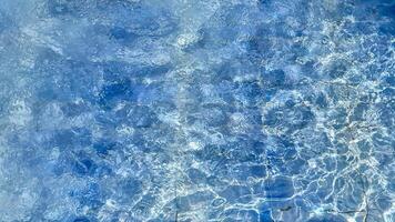Clear blue pool water sparkles under sunlight, perfect for summer themes, vacation relaxation, and promoting tranquility and refreshment photo