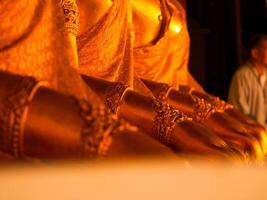 Close-up of details of golden Buddha hands arranged in a row in a Thai temple. photo