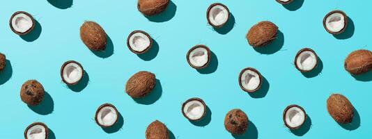 Creative layout of coconuts half on blue background. Tropical pattern, top view or flat lay. Hard light pop art minimal summer background. Horizontal banner photo