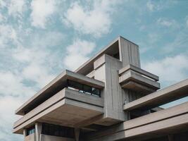 A modern, concrete building with geometric shapes and a cloudy sky.. photo