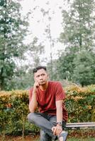 Southeast Asian man in a thoughtful pose, hand on chin with a focused expression. photo