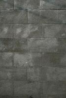 Textured grey stone wall with rectangular tiles, showing subtle patterns and weathered details. photo