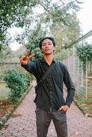Southeast Asian man showing a peace sign with two fingers, conveying positivity or harmony. photo