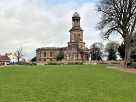 A large church with a clock tower in the middle of a field photo