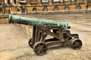 A cannon is sitting on the ground outside of a building photo